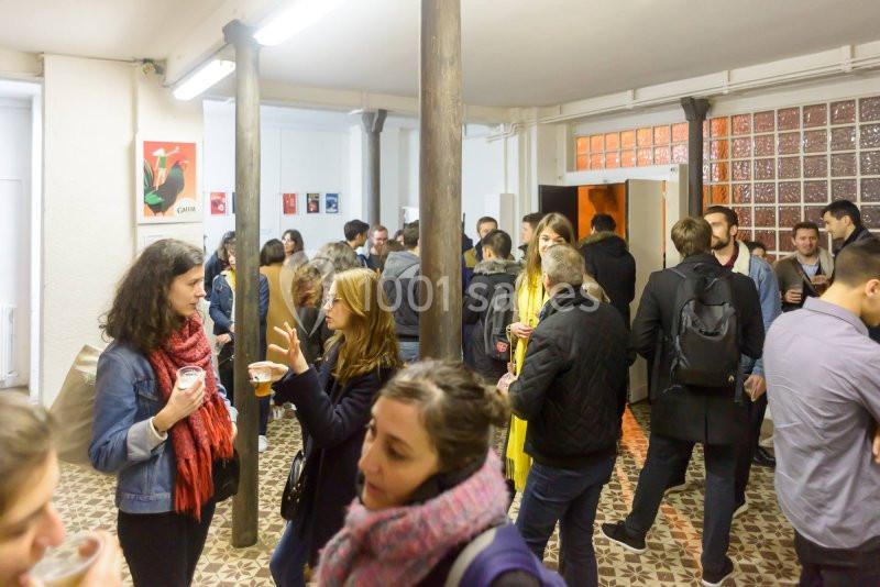 Des personnes discutent et partagent un moment convivial dans une salle lumineuse avec un sol en carreaux.