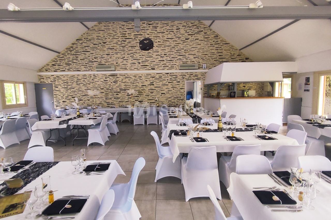 Salle de réception lumineuse avec tables dressées, nappes blanches et décoration élégante.