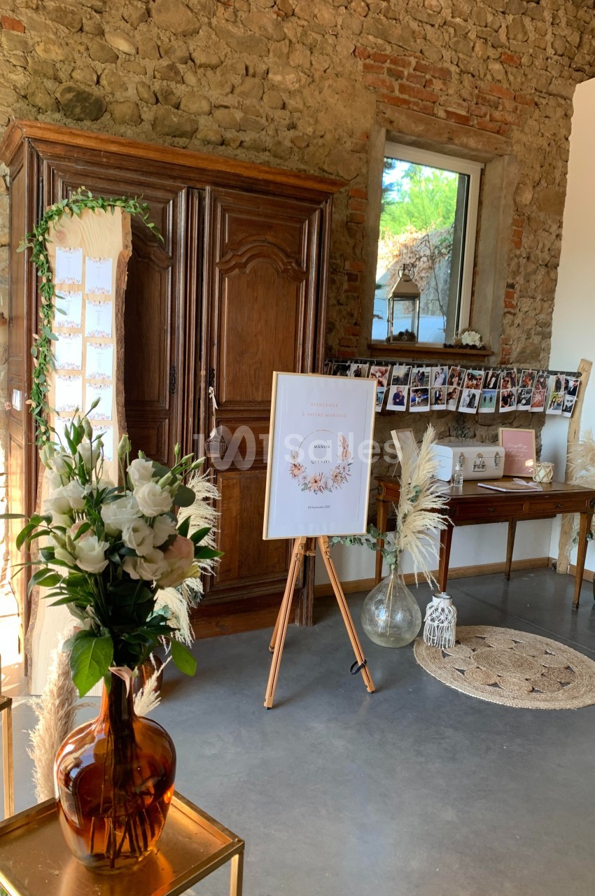 Décoration intérieure avec fleurs blanches, armoire en bois, photos suspendues et panneau sur chevalet dans une pièce en…