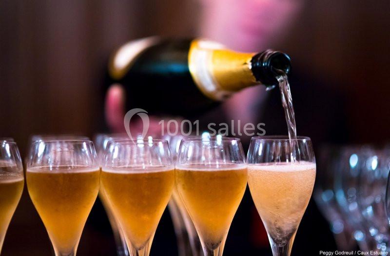 Un serveur verse du champagne dans plusieurs flûtes alignées sur une table.