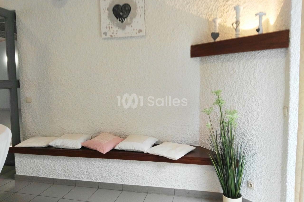 Banc en bois avec coussins, plante décorative et étagère murale ornée d'objets et d'un tableau.