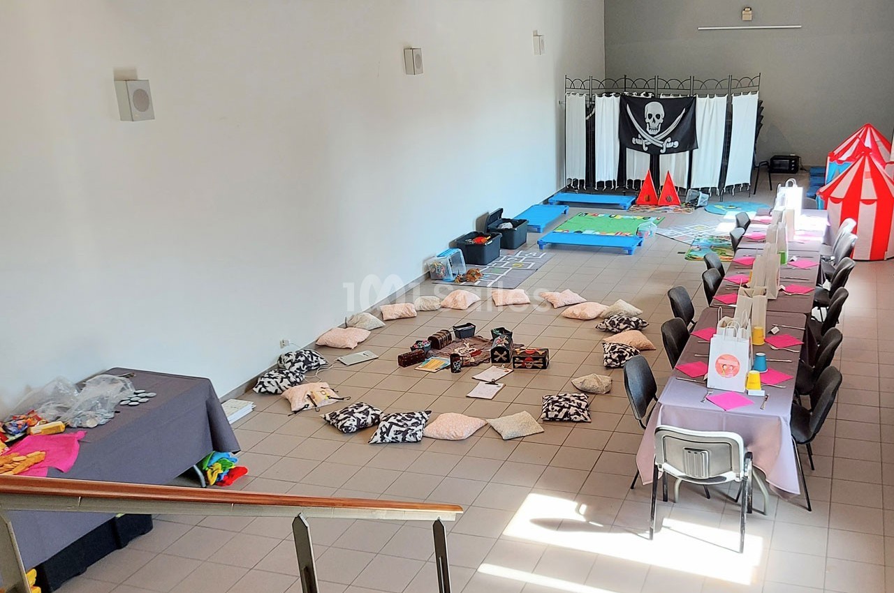 Salle aménagée avec des coussins disposés en cercle, une table décorée pour un repas et un décor sur le thème pirate.