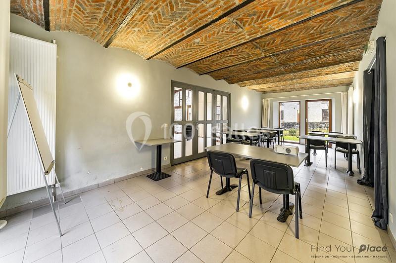 Salle de réunion lumineuse avec tables, chaises, tableau de présentation et plafond voûté en briques.