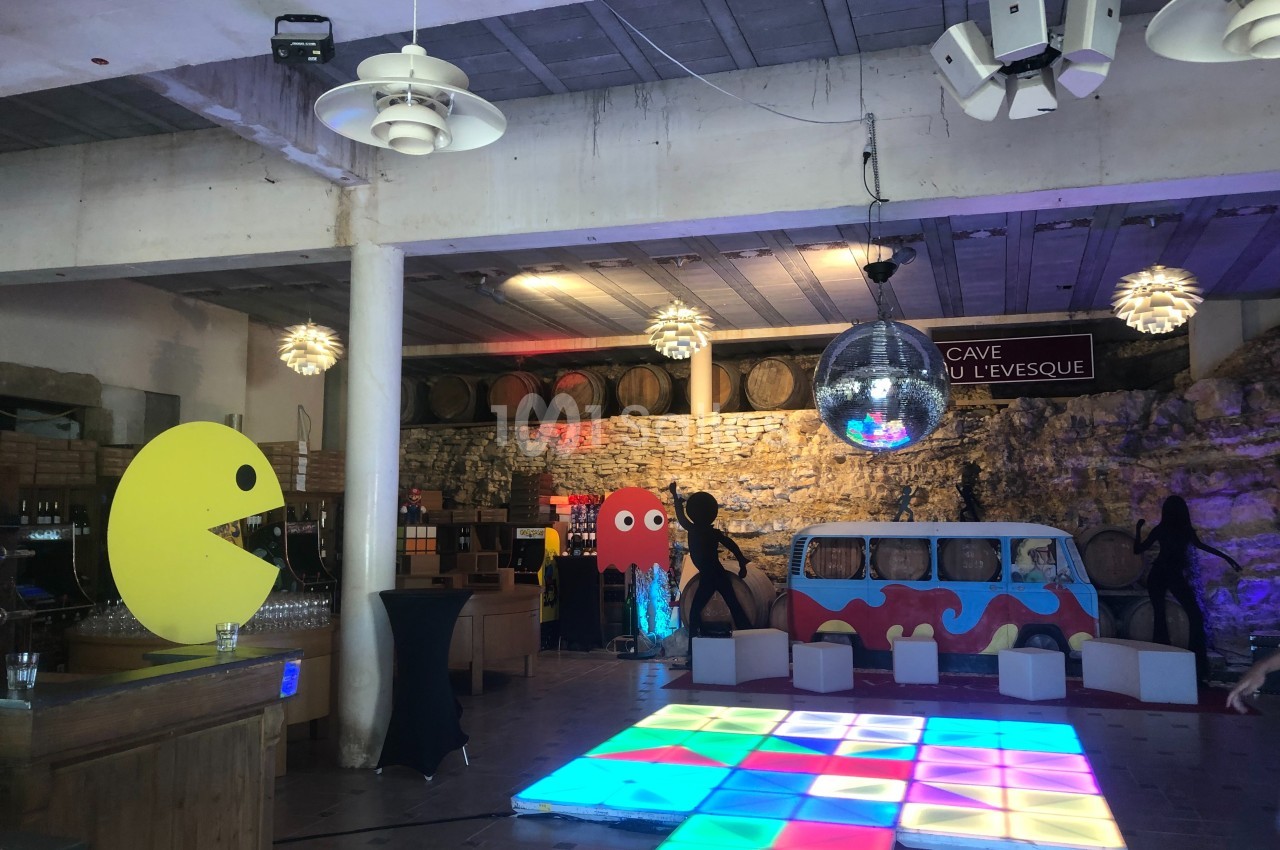 Salle décorée sur le thème rétro avec des éléments de Pac-Man, une piste lumineuse et un combi Volkswagen coloré.