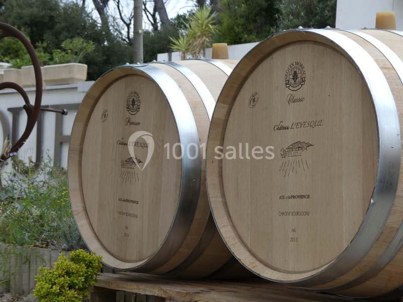 Deux tonneaux en bois gravés, posés à l'extérieur près de végétation et d'un mur clair.