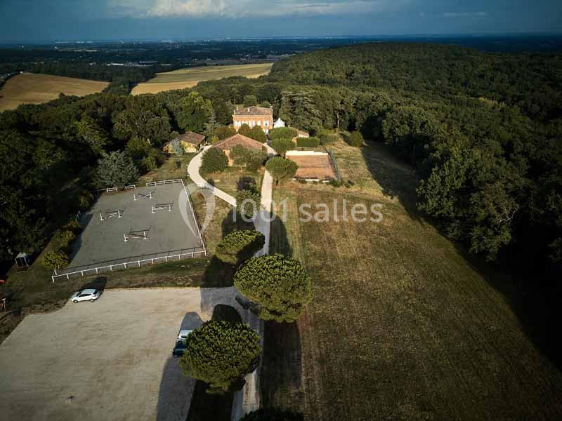 Vue aérienne d'une propriété entourée de champs, forêt, parking et installations équestres.