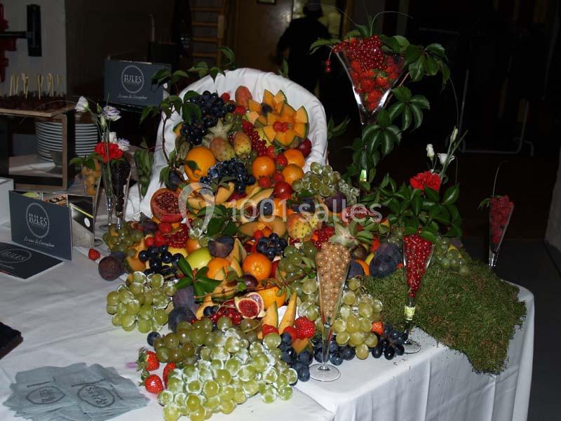 Présentation artistique de fruits variés, incluant raisins, figues, oranges et baies, disposés sur une table blanche.