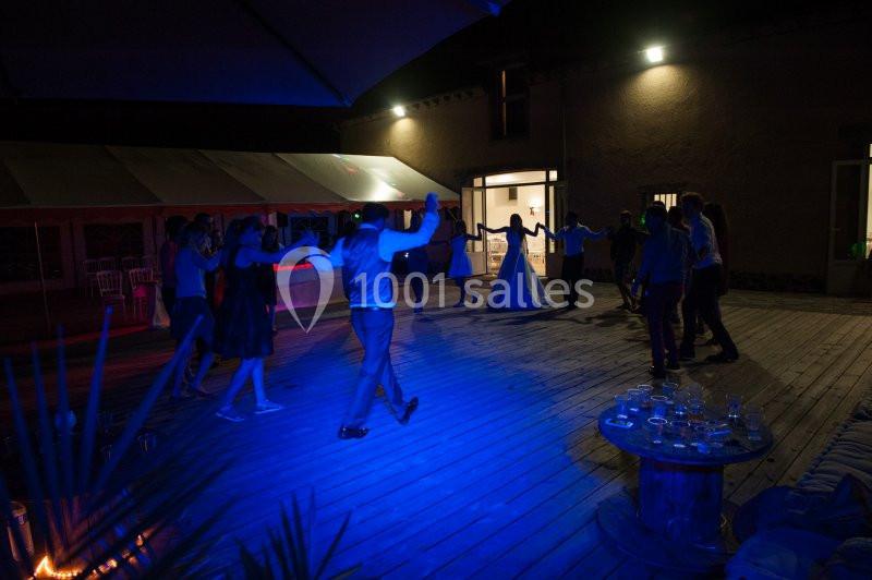 Groupe de personnes dansant sur une terrasse en bois éclairée par des lumières bleues en soirée.