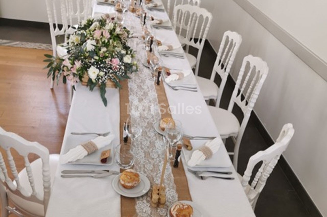 Table de réception décorée avec une nappe blanche, un chemin de table en dentelle, des fleurs et des couverts élégants.