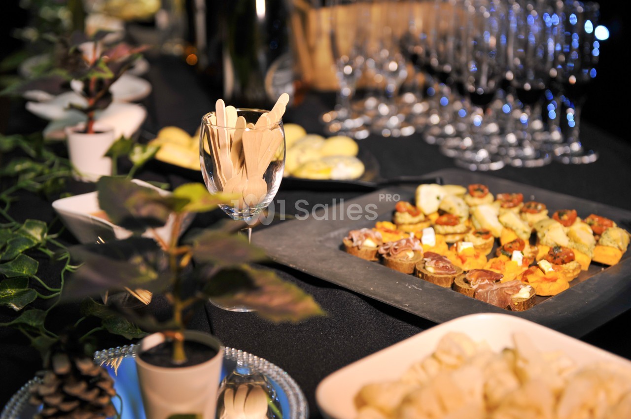 Plateau de canapés variés sur une table décorée avec des plantes, des verres à pied et des couverts en bois.