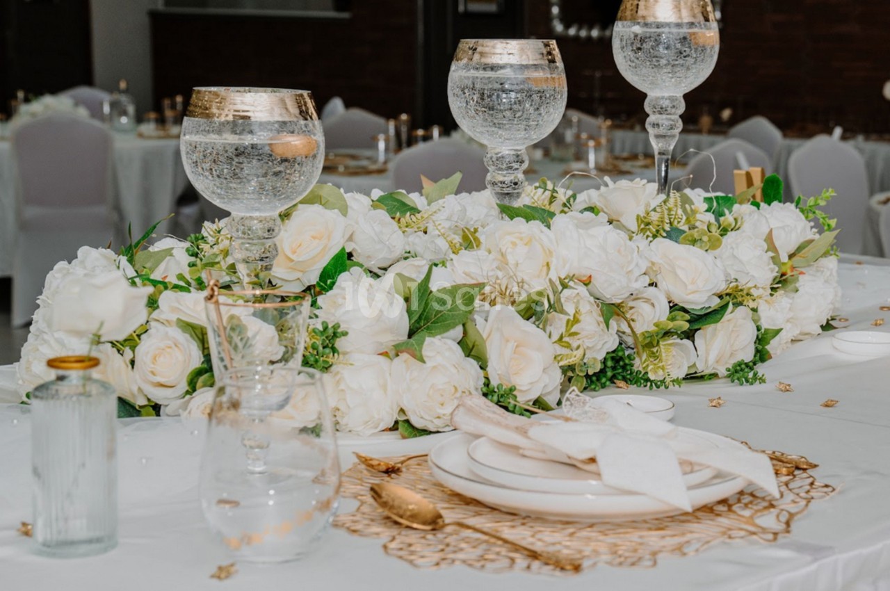 Table décorée avec des fleurs blanches, des verres élégants et une vaisselle raffinée dans un cadre de réception.