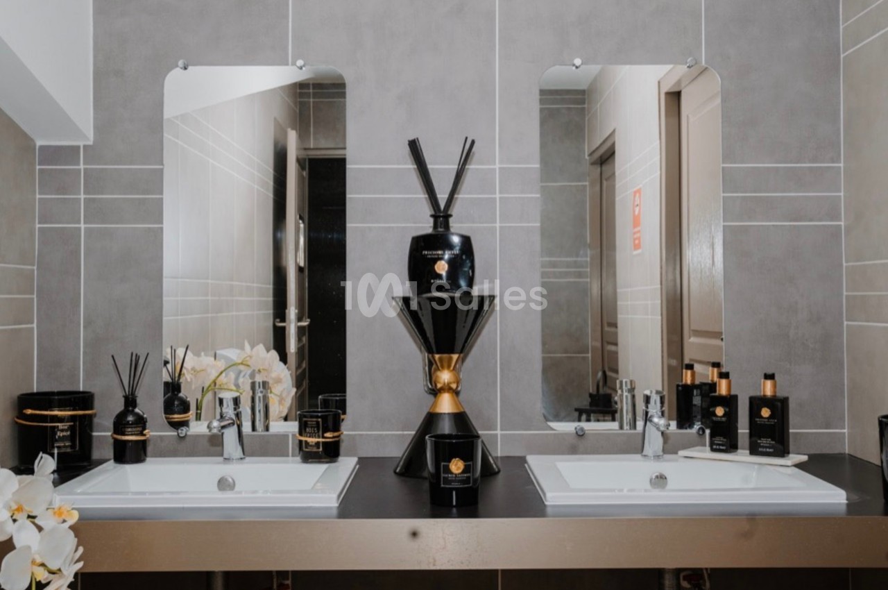 Deux lavabos avec miroirs, ornés de produits de soin et de décoration, dans une salle de bain moderne aux tons neutres.