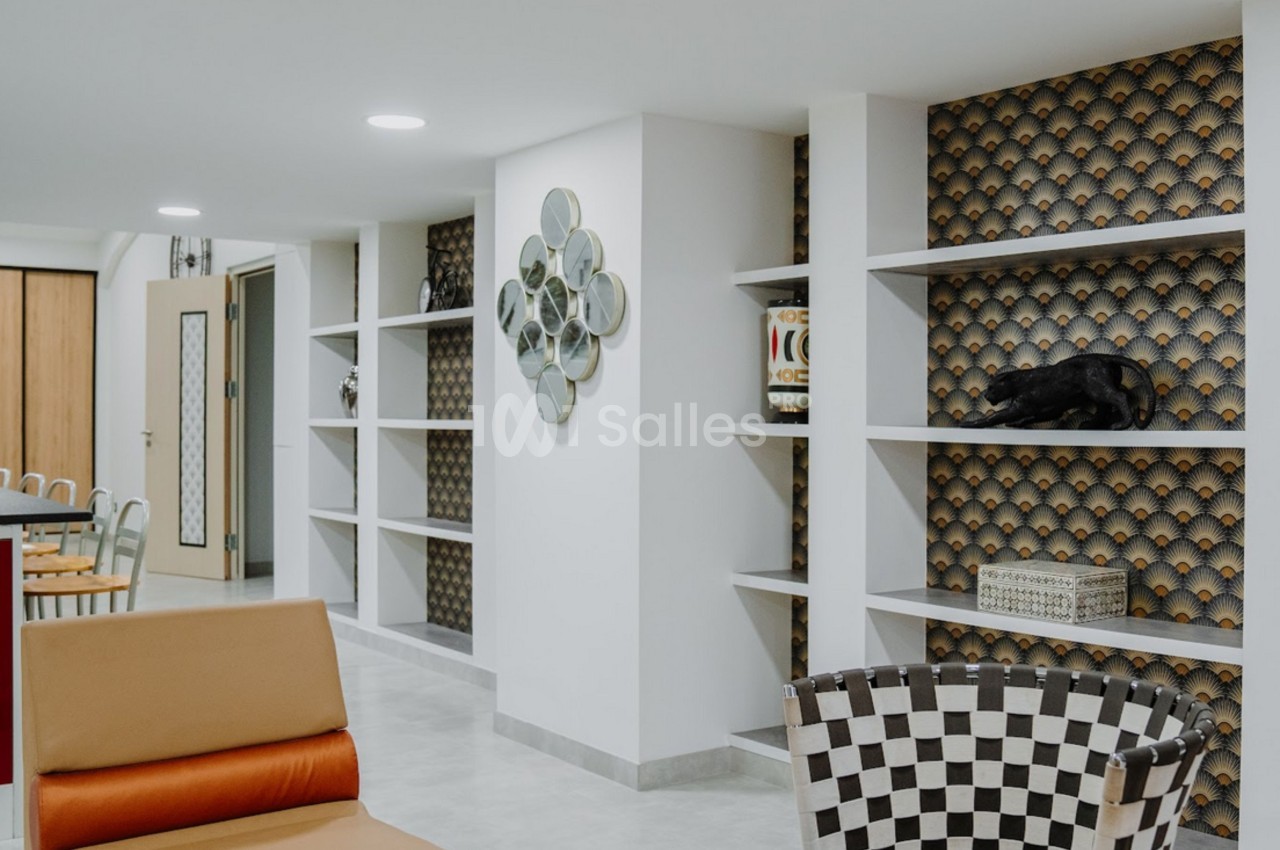 Espace intérieur moderne avec fauteuils, étagères décoratives et murs ornés de motifs géométriques.