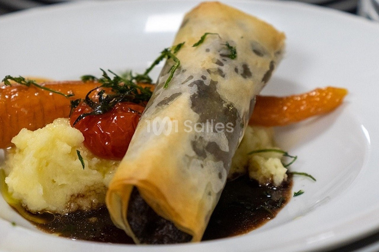 Feuilleté croustillant servi avec purée, carottes glacées, tomate confite et sauce brune sur une assiette blanche.