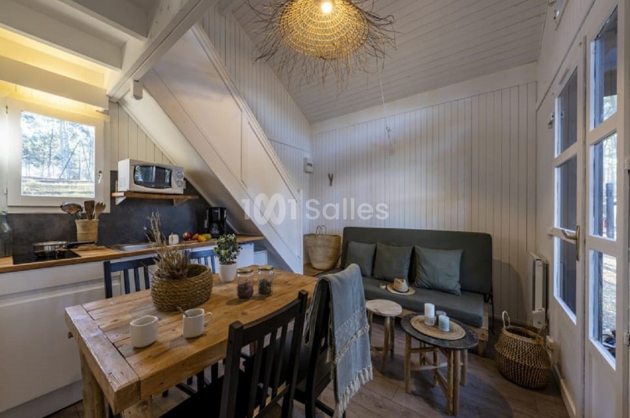 Intérieur d'une petite maison en bois avec cuisine ouverte, table en bois, canapé et décoration naturelle.