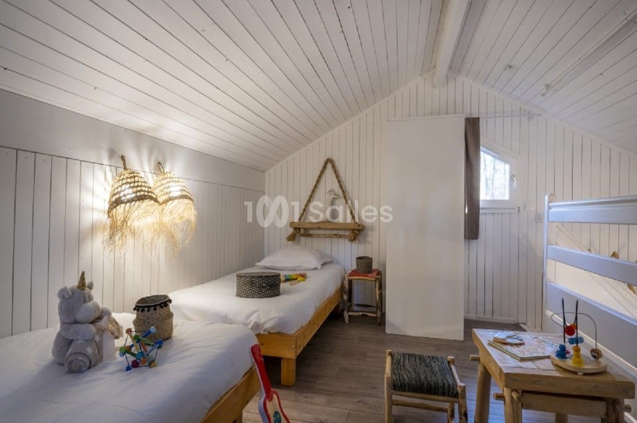 Chambre lumineuse avec deux lits simples en bois, jouets et décorations naturelles dans un style épuré.
