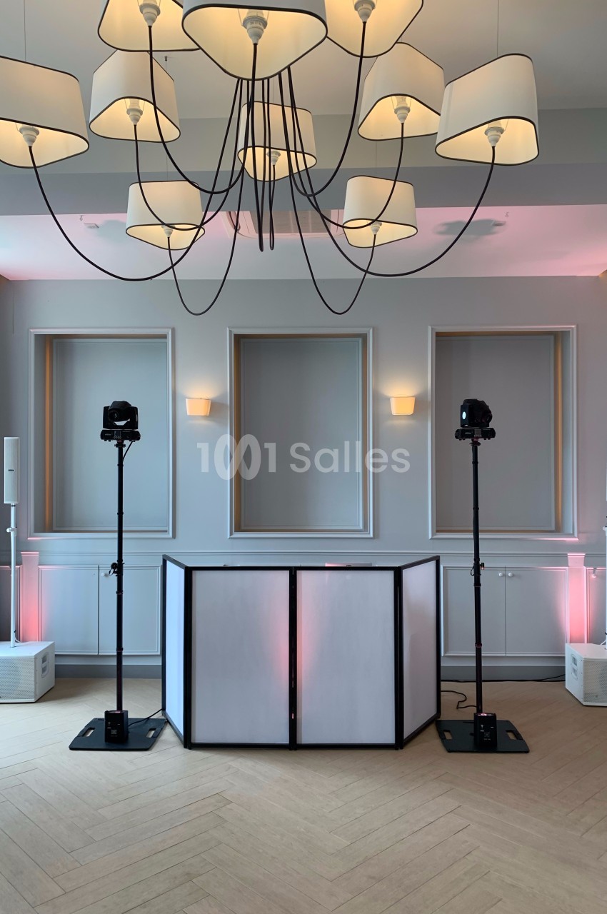 Installation d'équipements audio et d'éclairage avec une table blanche dans une salle lumineuse au design épuré.