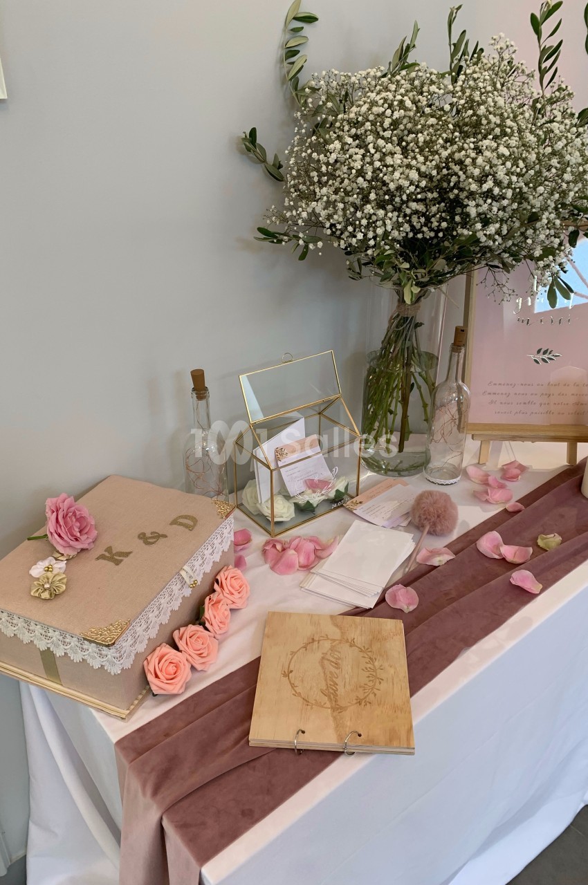 Décoration de table avec boîte personnalisée, fleurs roses et blanches, livre en bois et pétales pour un événement festif.