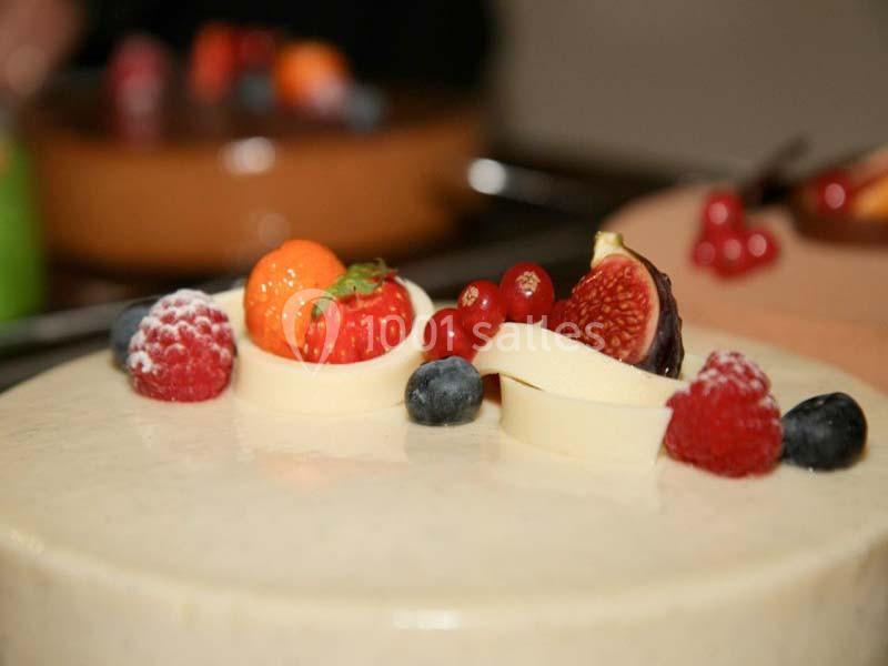 Gâteau décoré de fruits rouges, figue, myrtille et spirales de chocolat blanc sur un glaçage lisse.