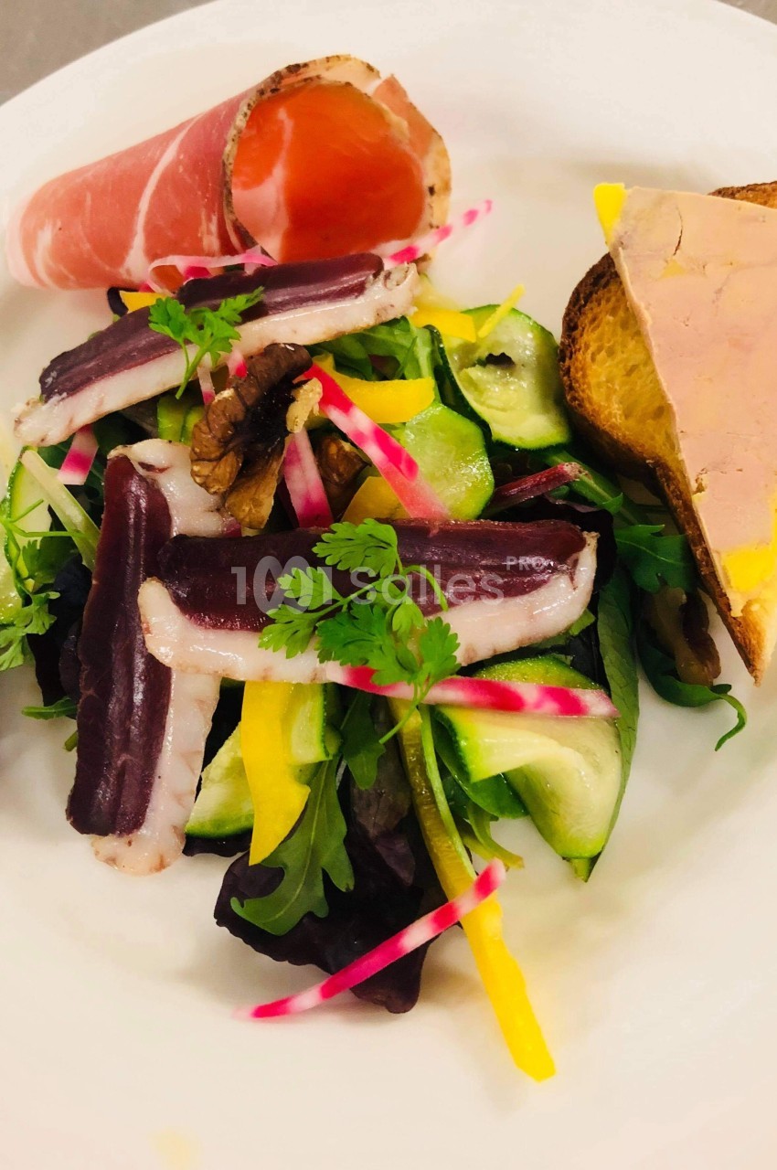 Assiette composée de salade verte, magret de canard fumé, légumes croquants, foie gras sur toast et tranche de jambon.