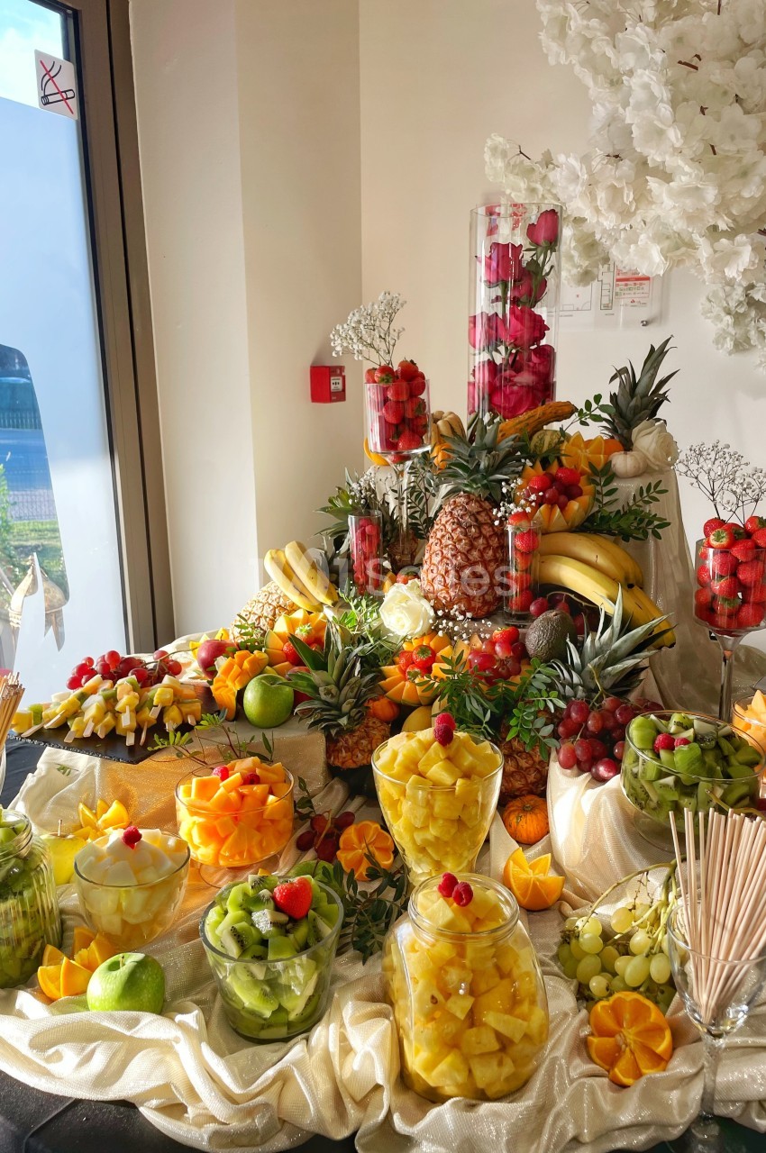Buffet coloré de fruits frais variés, disposés sur une table décorée avec des fleurs et des éléments élégants.