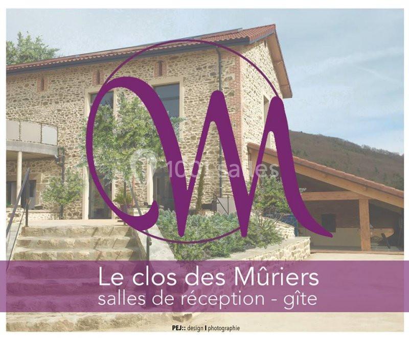 Façade en pierre d'un bâtiment avec terrasse, entourée de verdure, utilisée comme salle de réception et gîte.