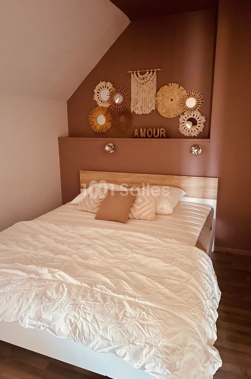Chambre avec lit double, mur décoré de miroirs ronds et d'une suspension murale, ambiance chaleureuse et épurée.