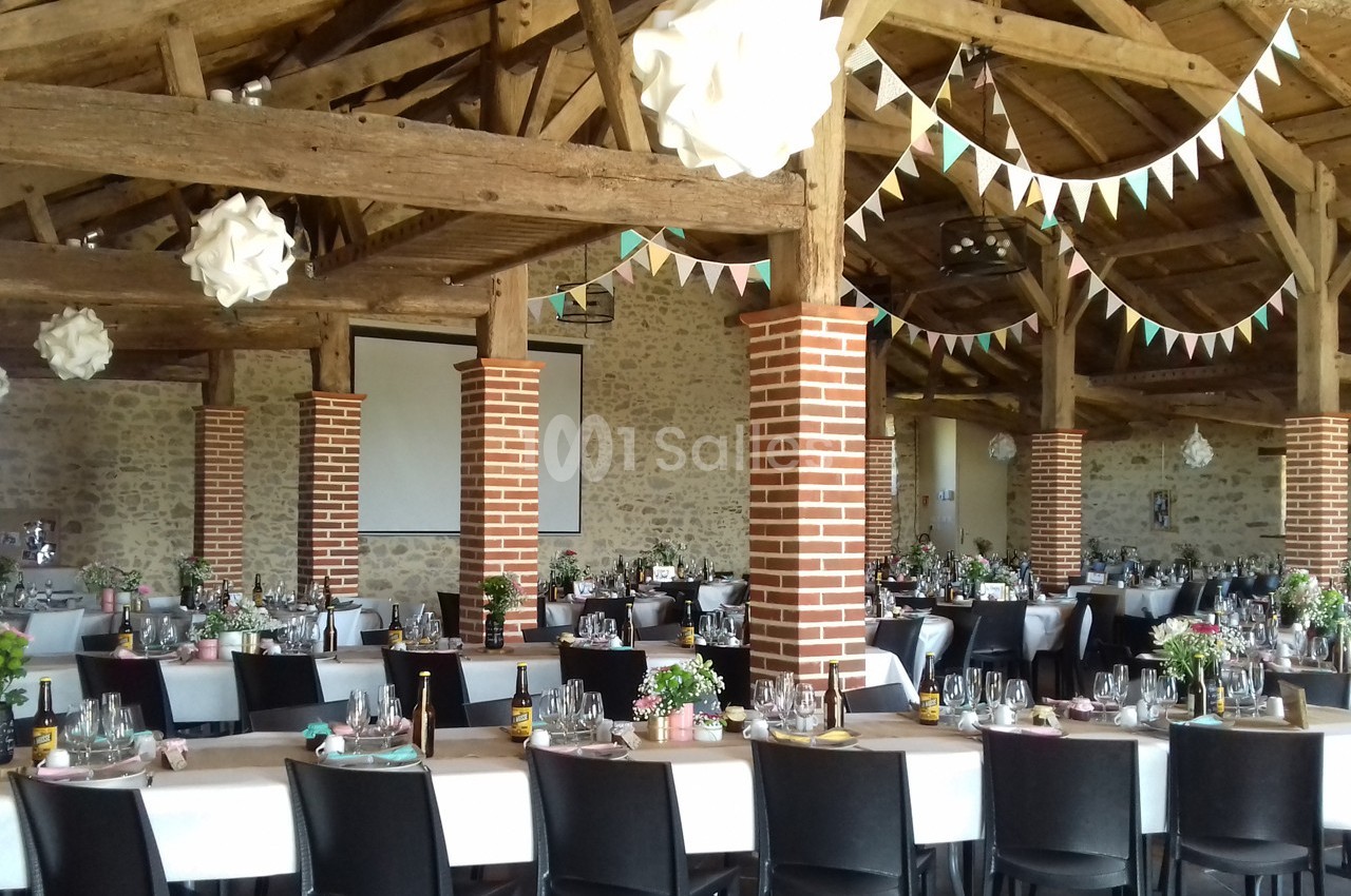 Salle de réception décorée avec des guirlandes et des tables dressées pour un événement festif.