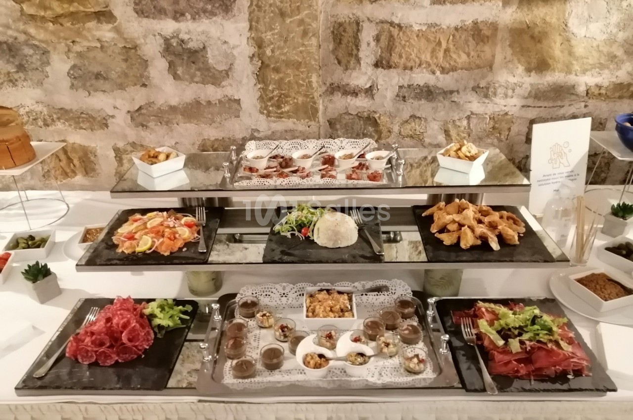 Buffet composé de plats variés tels que charcuteries, salades, desserts et amuse-bouches, présenté sur des plateaux.