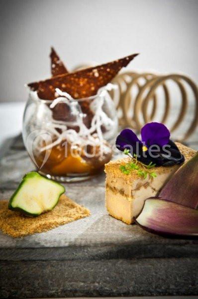 Assiette gastronomique avec foie gras, décoration florale, courgette, artichaut et verrine garnie de croustillants.