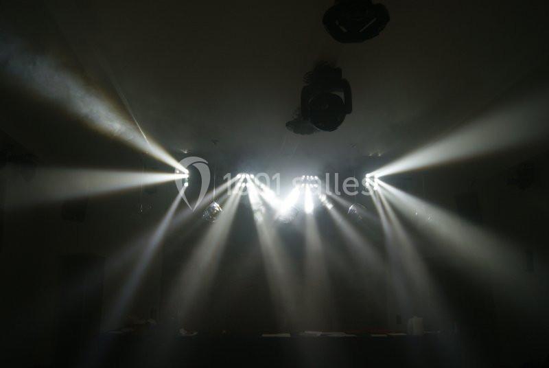 Des faisceaux de lumière blanche émanant de projecteurs dans une salle sombre.