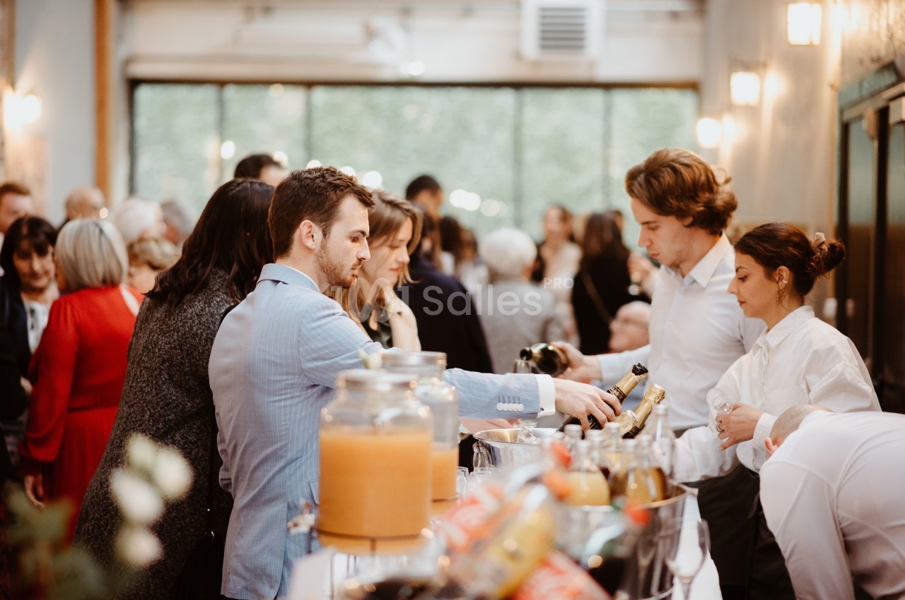 Des personnes se servent à un buffet dans un espace lumineux avec de grandes fenêtres et une ambiance conviviale.