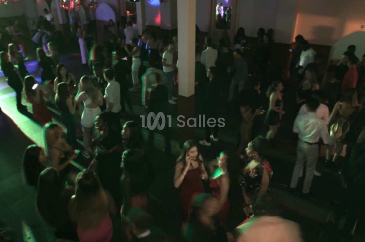 Groupe de personnes dans une salle sombre, éclairée par des lumières colorées, lors d'un événement festif.