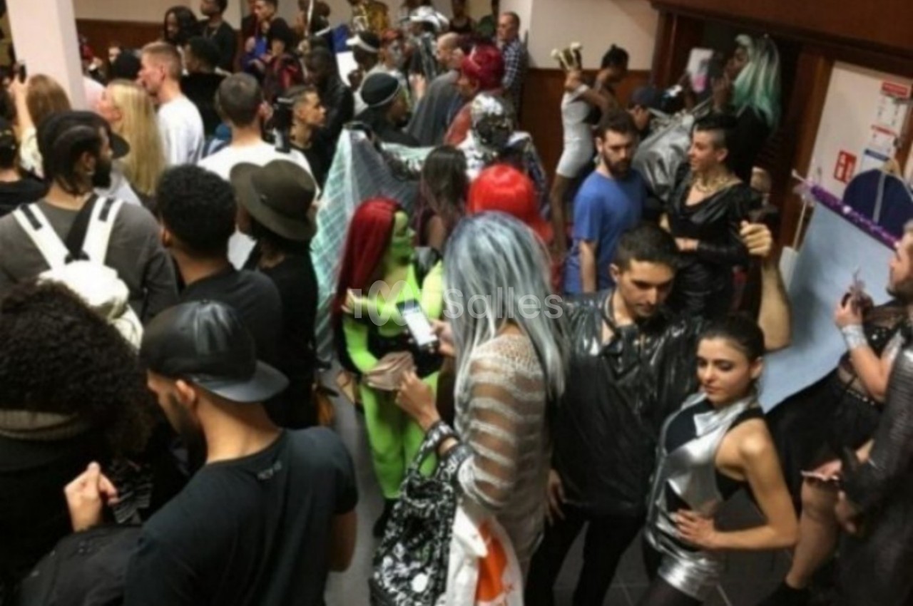 Groupe de personnes en tenues variées lors d'un événement intérieur animé.