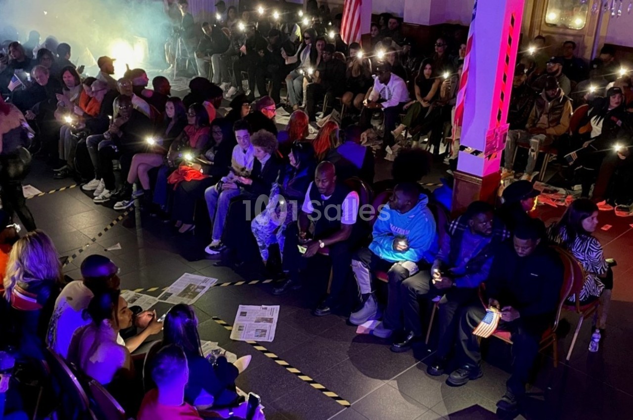 Un groupe de personnes assises dans une salle sombre, éclairées par des lumières de téléphone portable.