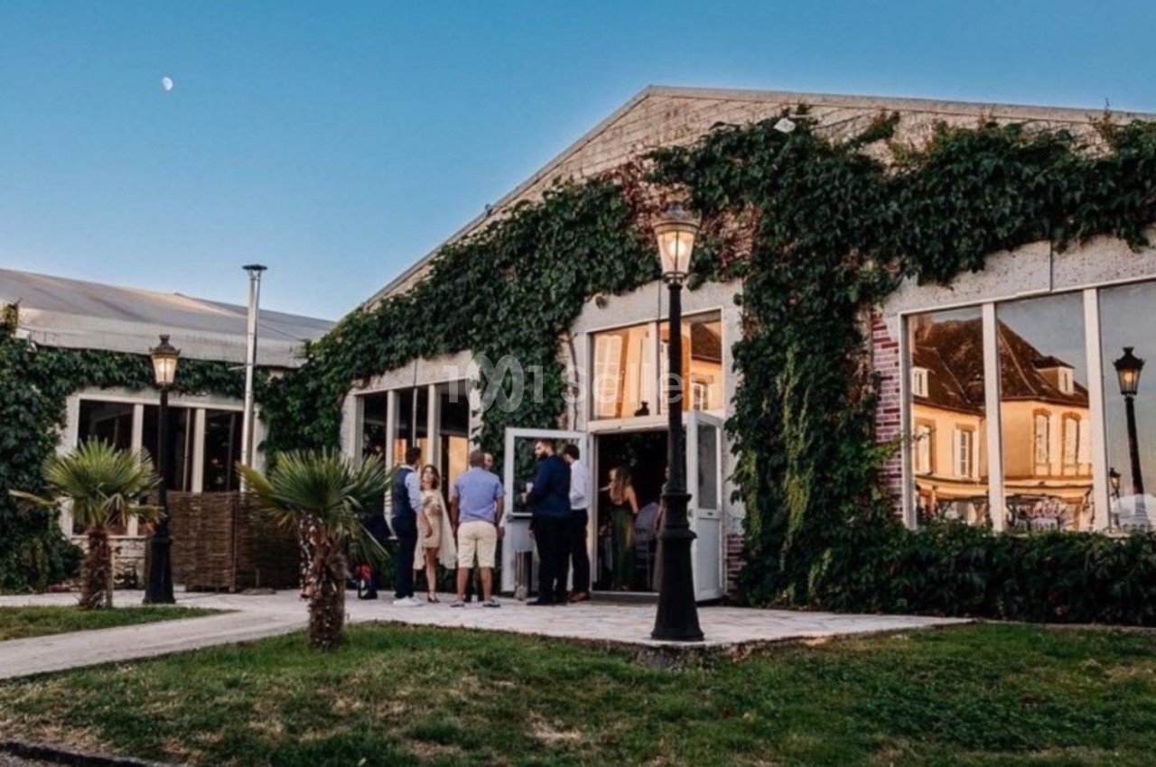 Bâtiment recouvert de lierre avec de grandes fenêtres, des lampadaires et un groupe de personnes à l'entrée.
