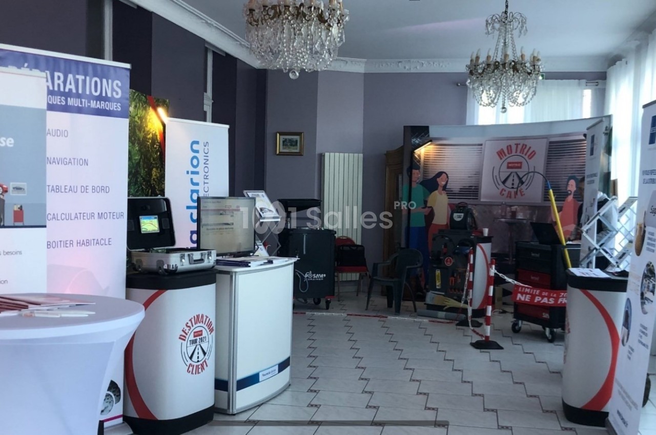 Salle d'exposition avec stands promotionnels, affiches et équipements automobiles sous un éclairage naturel.