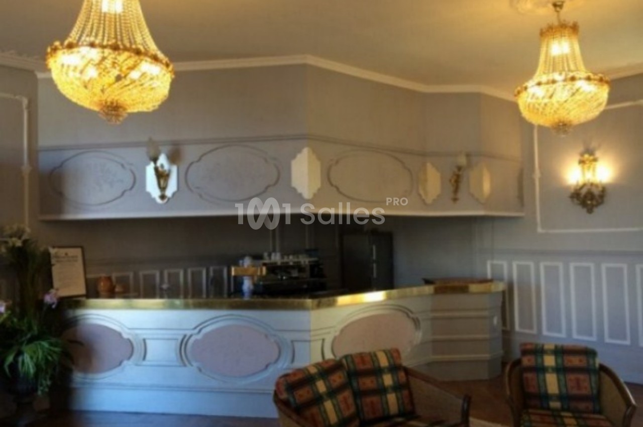 Intérieur d'une pièce élégante avec un comptoir en bois clair, lustres en cristal et fauteuils à motifs.