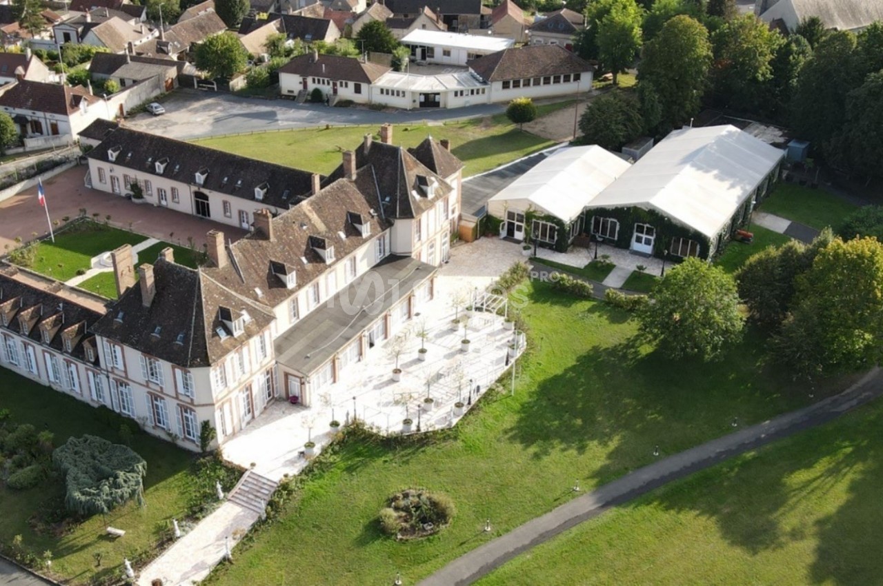 Vue aérienne d'un grand bâtiment historique entouré de jardins, avec des structures modernes et des espaces verts à…