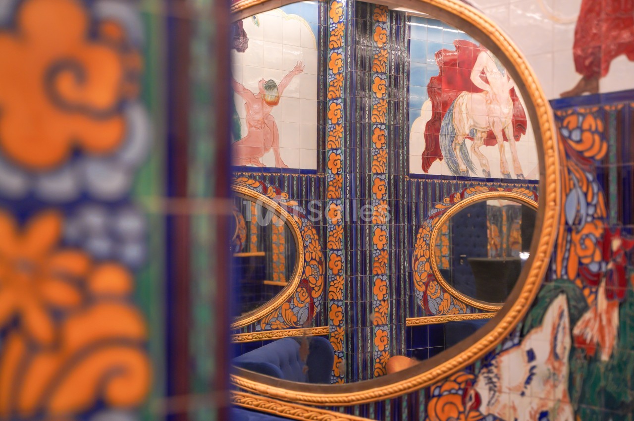 Miroirs ronds dorés reflétant des carreaux colorés ornés de motifs et illustrations dans un décor vibrant.