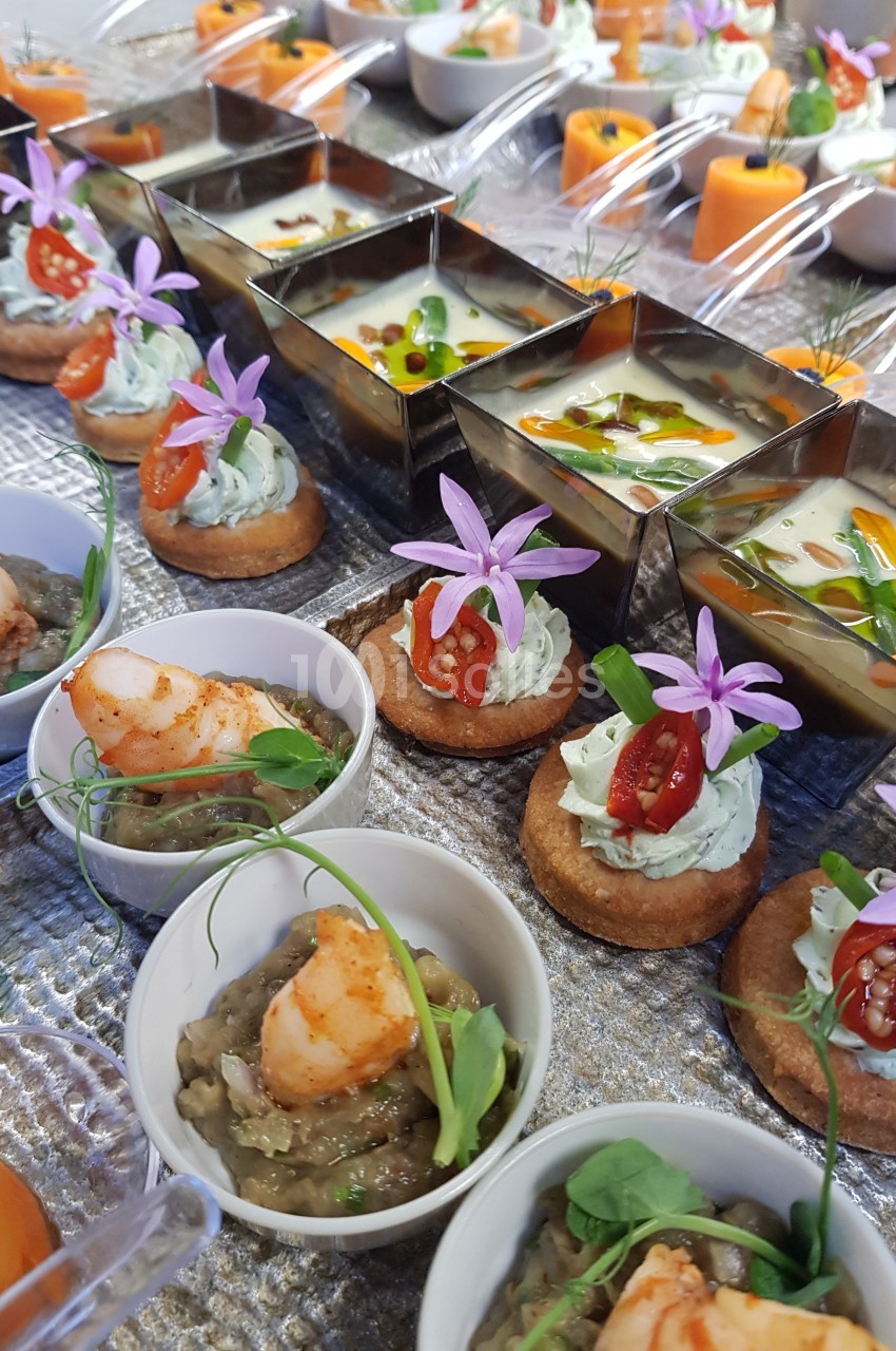Assortiment de bouchées apéritives colorées comprenant verrines, toasts garnis et petites portions de crevettes.