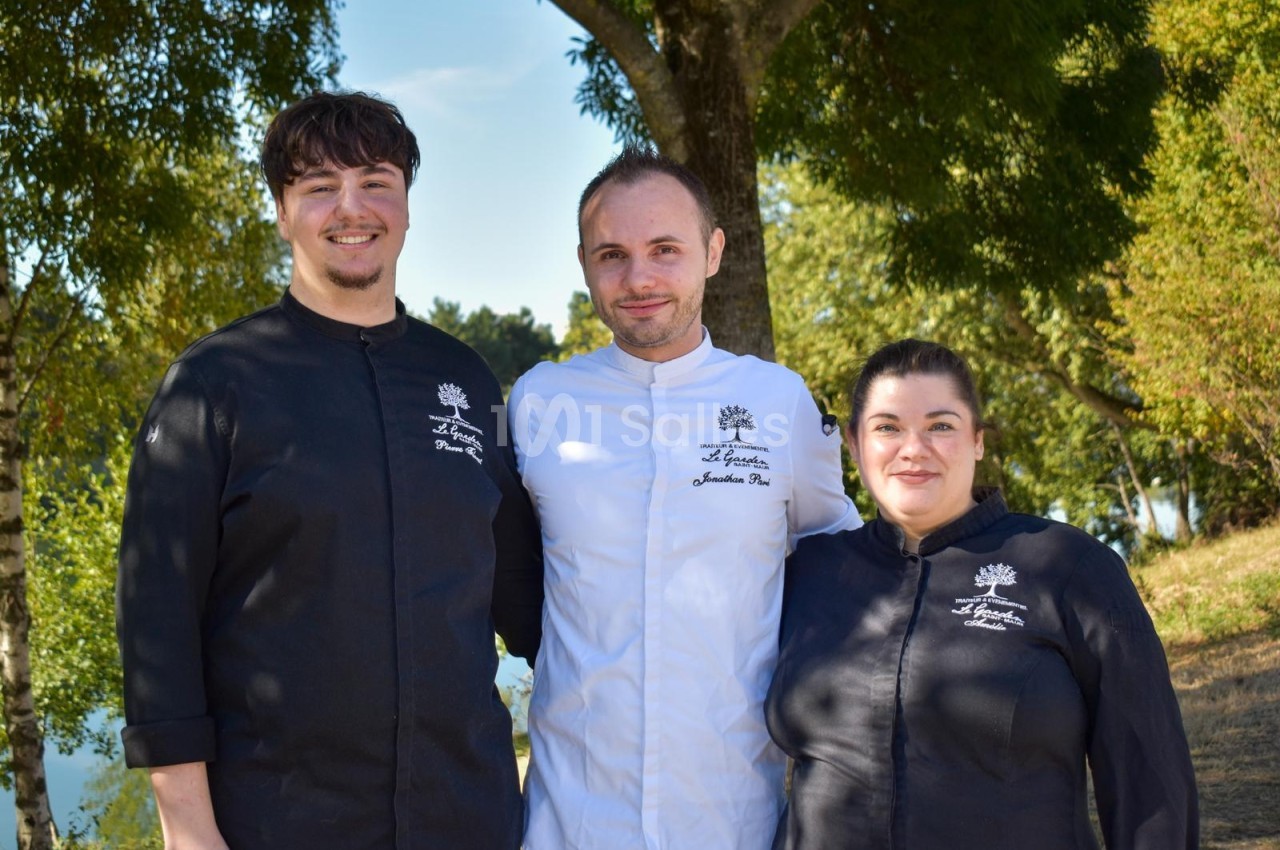Trois membres du personnel en tenue professionnelle posent sous des saules au bord de l'eau.