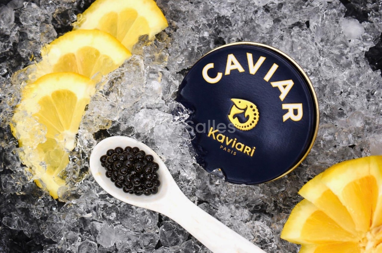 Caviar noir en cuillère, citrons frais et boîte de caviar sur lit de glaçons.