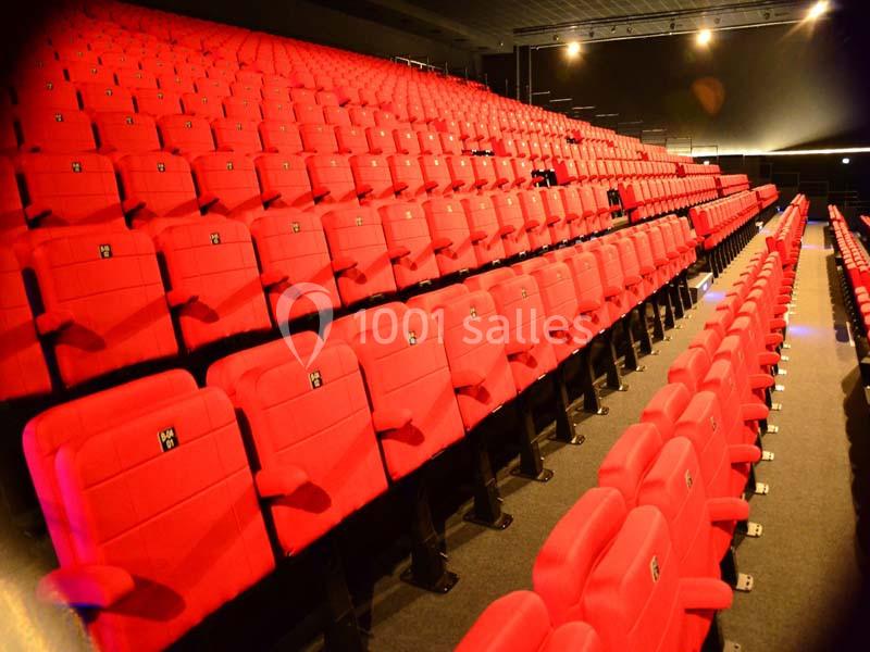 Rangées de sièges rouges vides dans une salle de spectacle ou de cinéma éclairée.