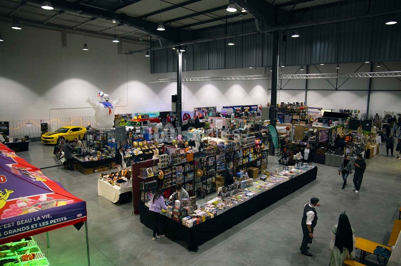 Vue d'ensemble d'un salon avec des stands de produits variés, des visiteurs et une décoration intérieure lumineuse.