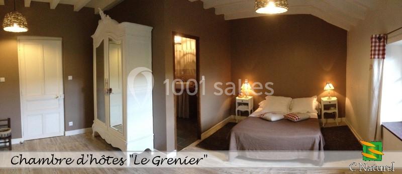 Chambre d'hôtes avec lit double, armoire blanche, éclairage chaleureux et salle de bain attenante.