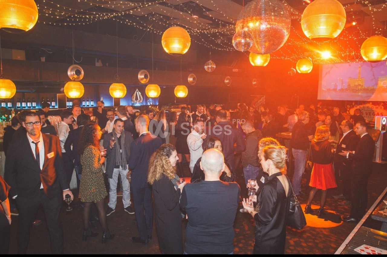 Groupe de personnes socialisant dans une salle décorée de guirlandes lumineuses et de boules disco.
