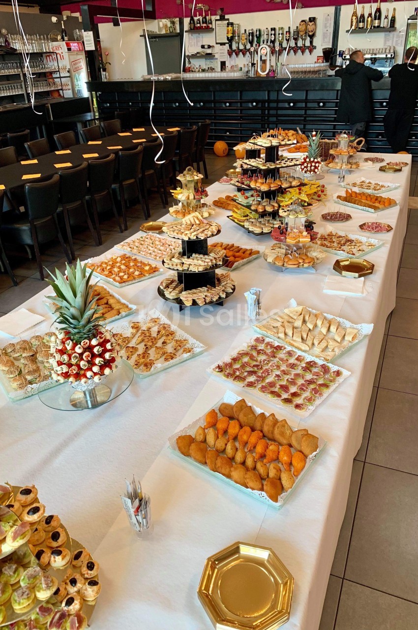 Buffet de réception avec une grande variété de plats salés et sucrés disposés sur des tables décorées.