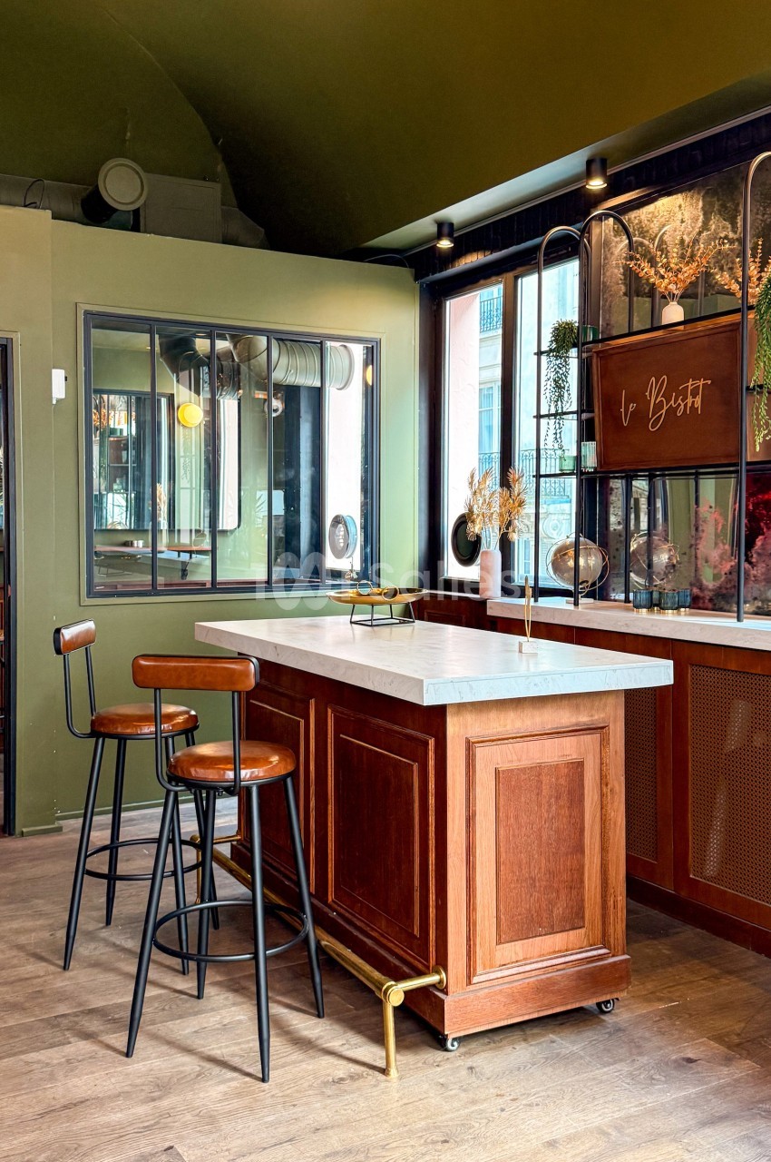 Comptoir en bois avec plateau en marbre, tabourets hauts et décorations végétales dans un intérieur au design moderne.