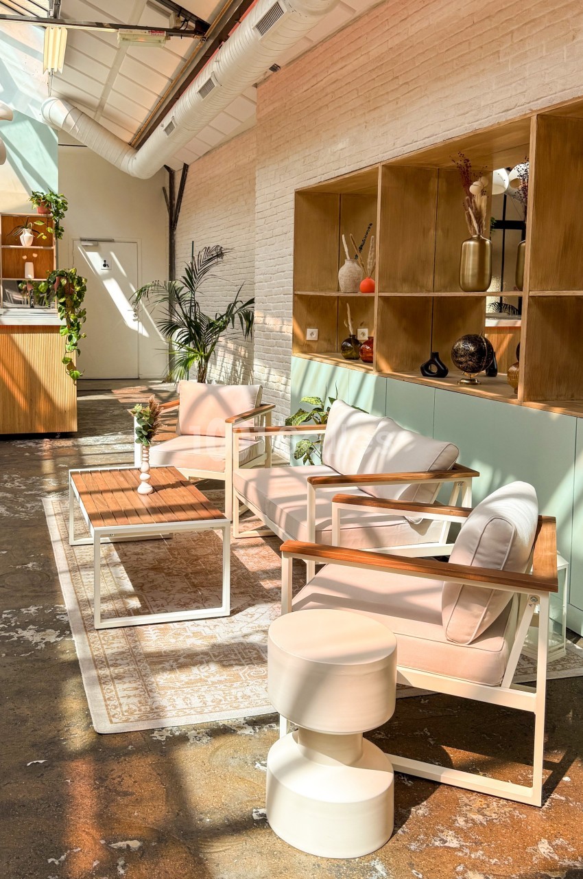 Espace lumineux avec mobilier moderne, murs en briques blanches, étagères en bois et plantes décoratives.